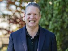 Photo of Dr. Richard Lane, smiling with greenery behind him